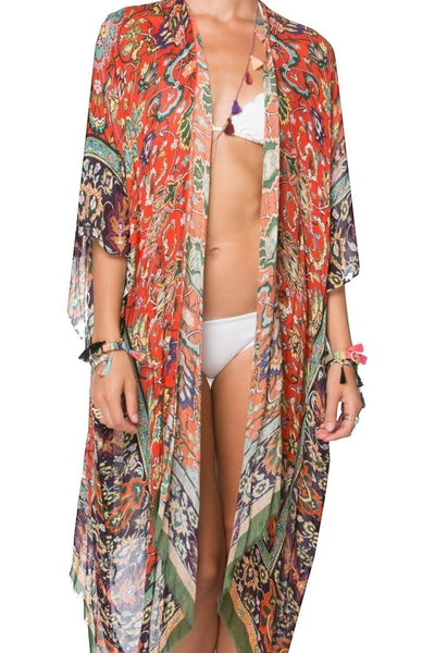 Model wearing a long Subtle Luxury modal kimono coverup in a vibrant orange and green masala print with raw edges. 3